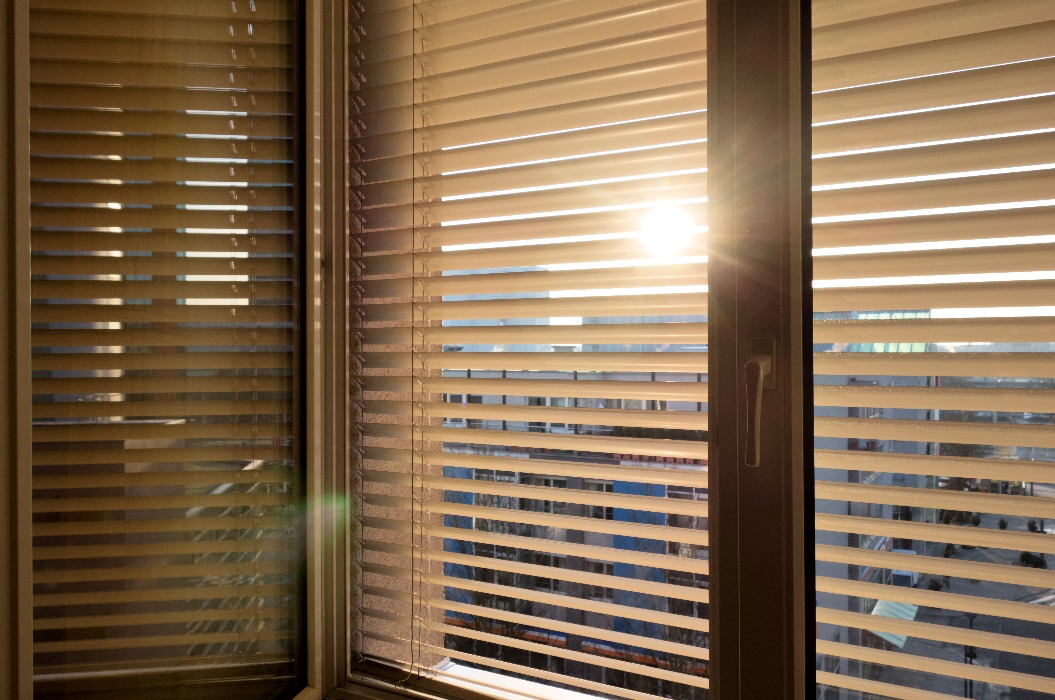 Jalousien als Sonnenschutz am Fenster