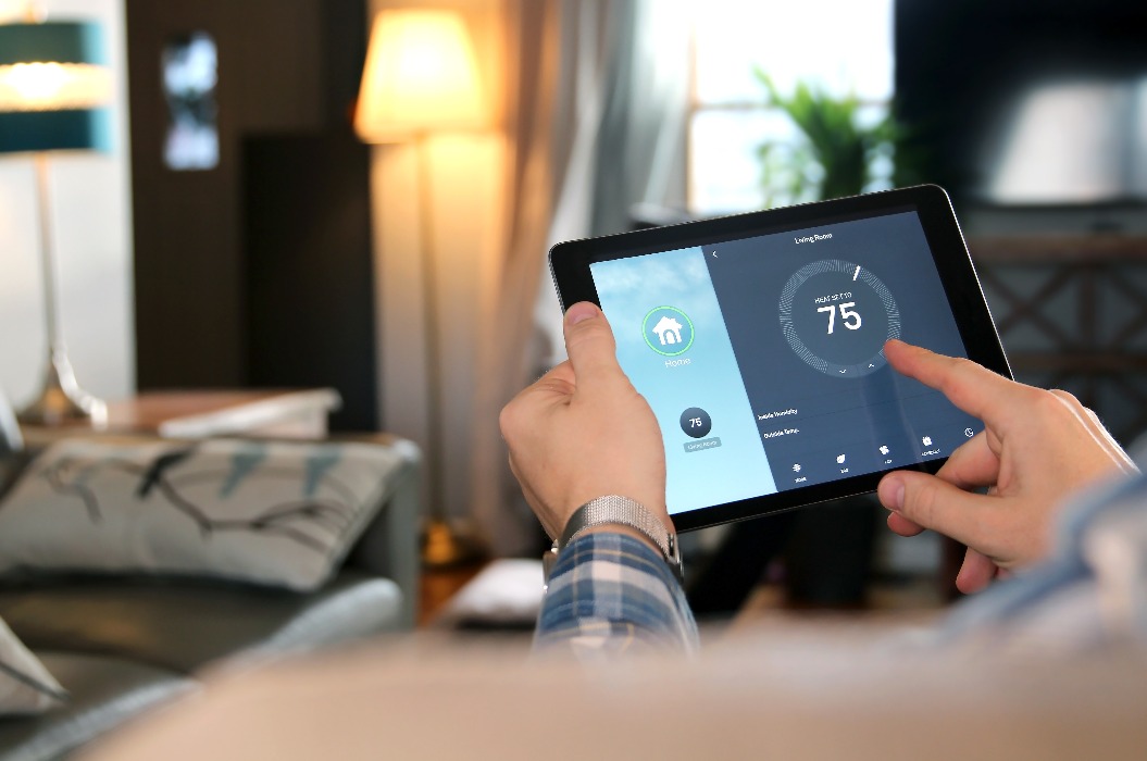 Der Mann reguliert die Temperatur mithilfe eines Tablets mit Smart-Home-Funktion.