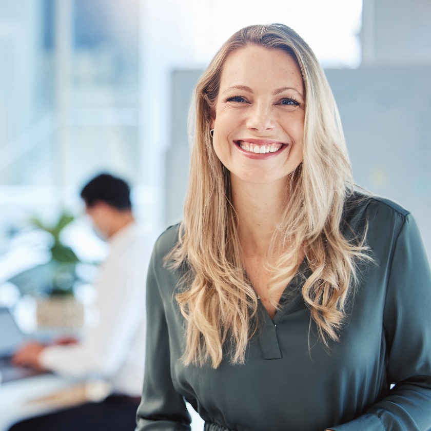 Female leader, manager or CEO with a smile, mission and vision in the office and her team in the background. Leadership, management and success with a woman boss and corporate business people at work